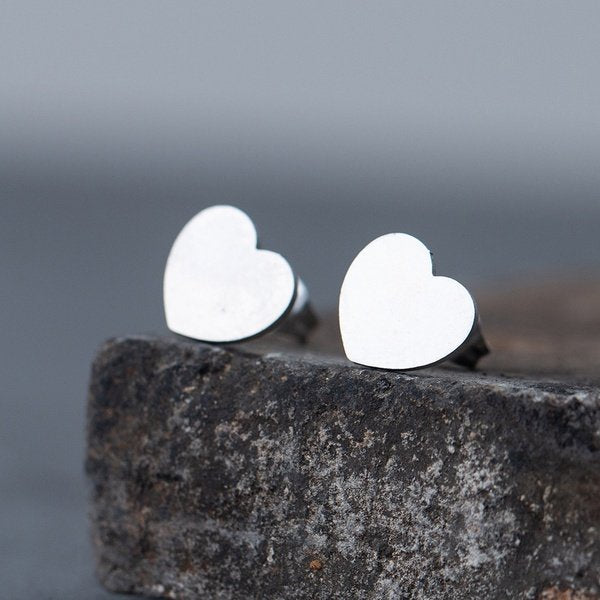 Aretes de corazón de acero inoxidable plateados.